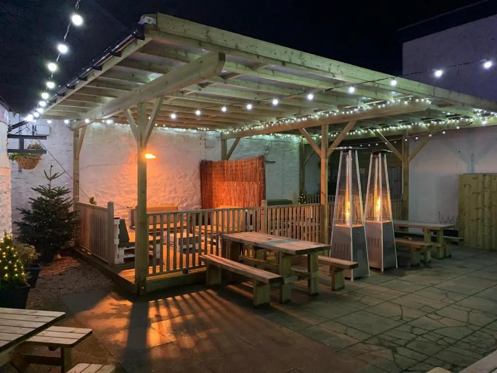 a patio with benches and umbrellas at night at New Inn Hotel in Ellon