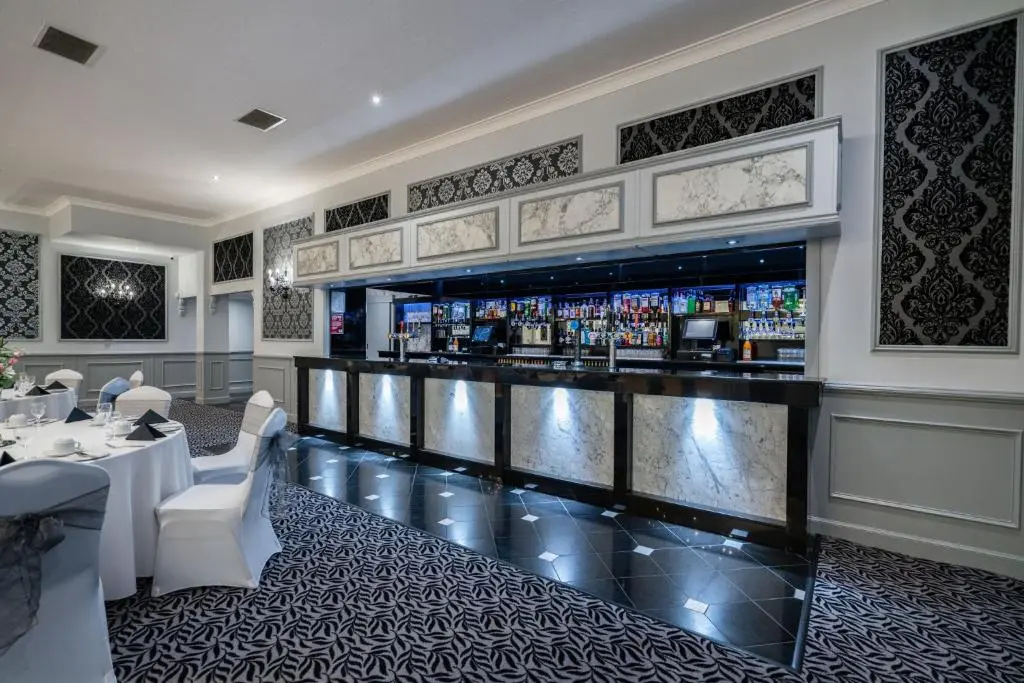 a bar in a restaurant with white tables and chairs at New Inn Hotel in Ellon