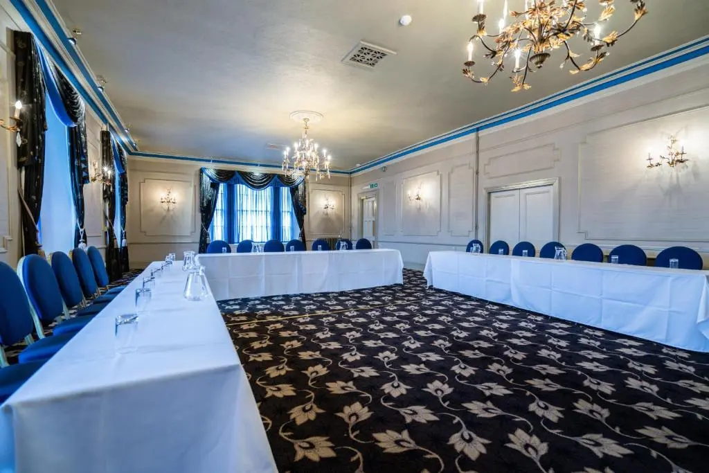 a conference room with white tables and chairs and a chandelier at New Inn Hotel in Ellon