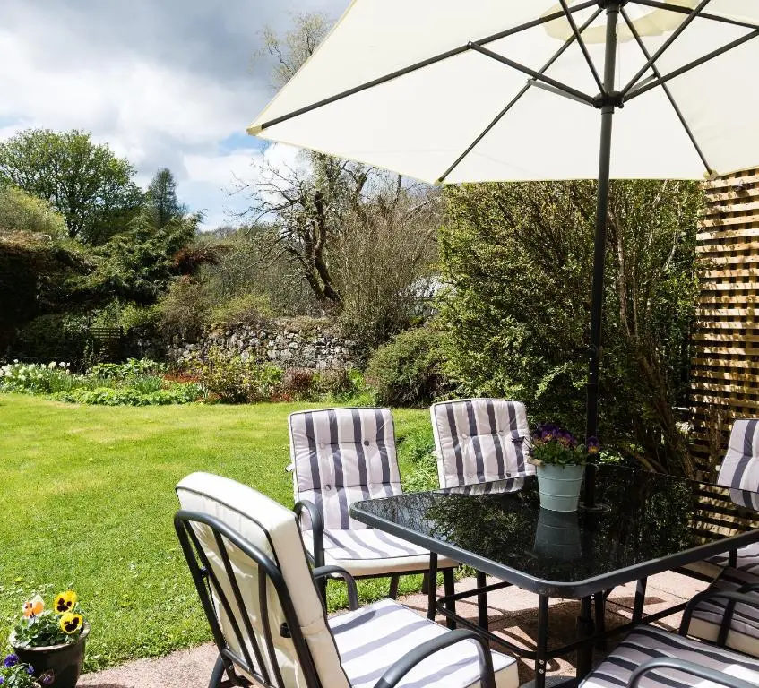 a table and chairs with an umbrella on a patio at Smithy Cottage in Kirkmichael