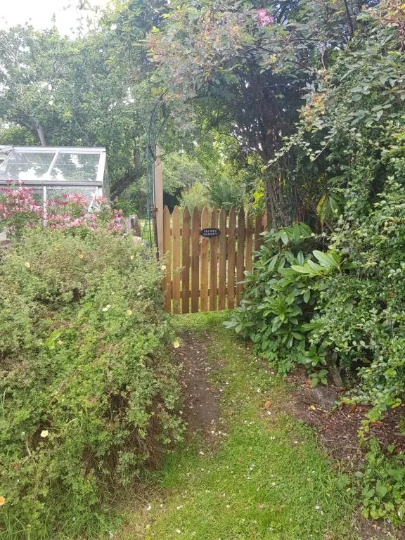a garden with a wooden fence and some bushes at Smithy Cottage in Kirkmichael