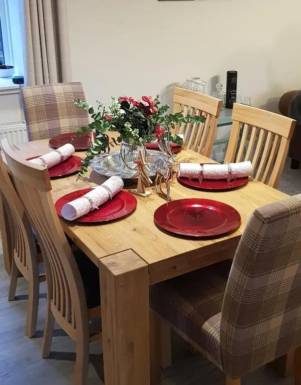 a wooden table with red plates and napkins on it at Smithy Cottage in Kirkmichael