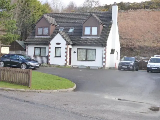 a house with two cars parked in a driveway at Dacama House Accommodation in Ullapool
