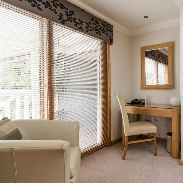 a living room with a desk and a chair next to a window at The Redgarth in Oldmeldrum