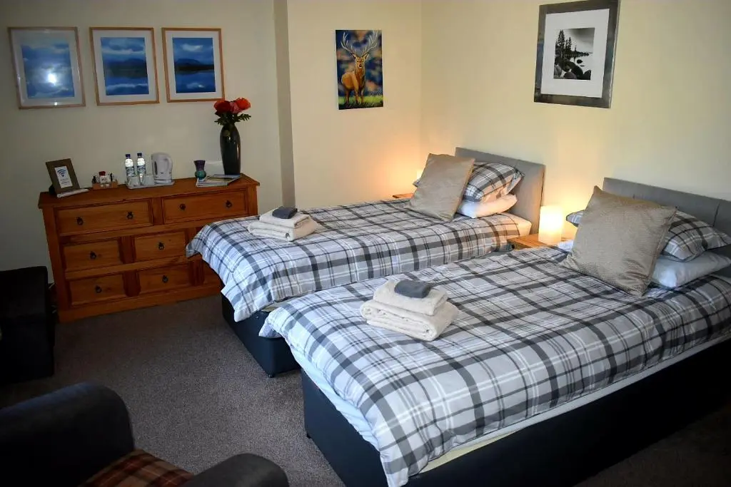 a bedroom with two beds and a wooden dresser at Lycia Rooms + in Inverness