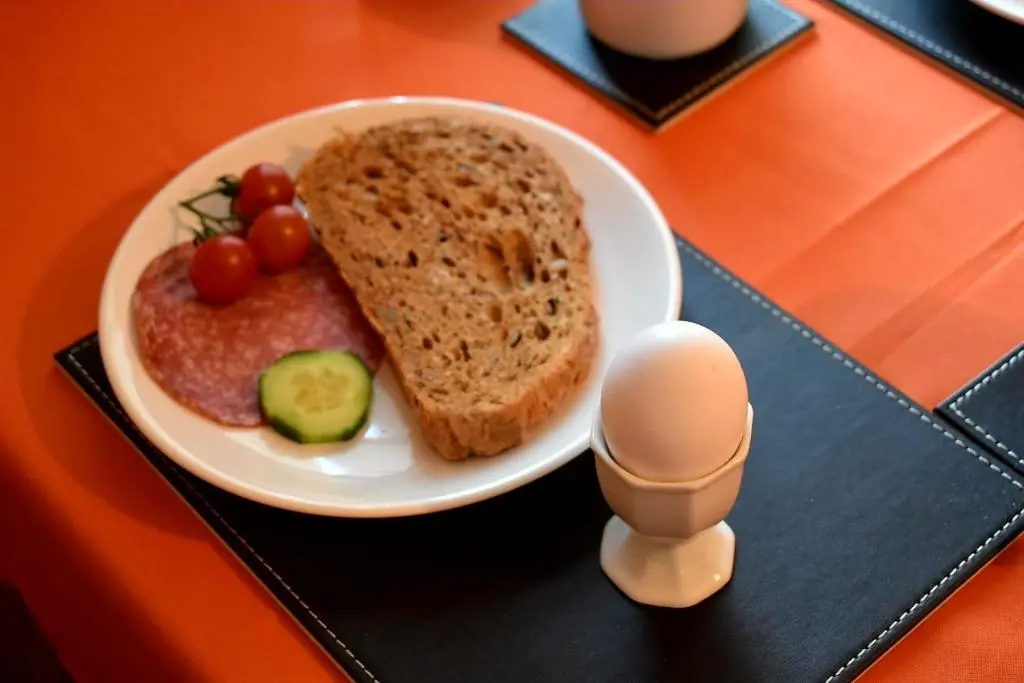 a plate of food with bread and an egg on a table at Lycia Rooms + in Inverness