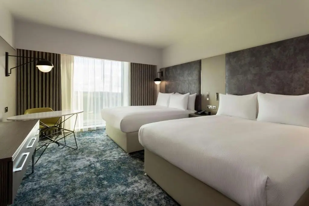 a hotel room with two beds and a desk at Hilton Aberdeen TECA in Aberdeen
