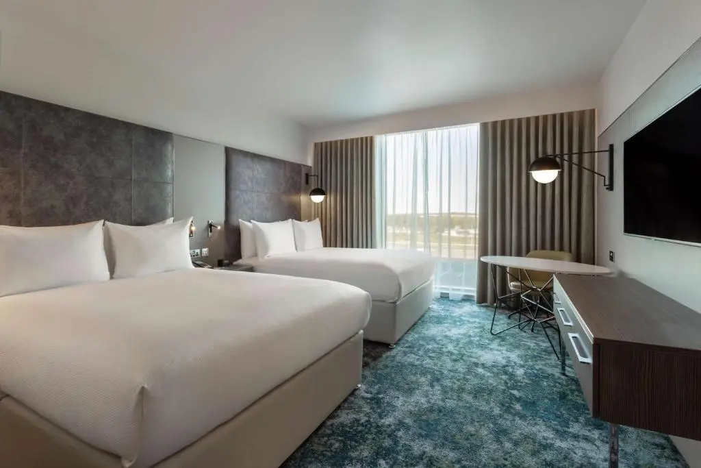 a hotel room with two beds and a flat screen tv at Hilton Aberdeen TECA in Aberdeen