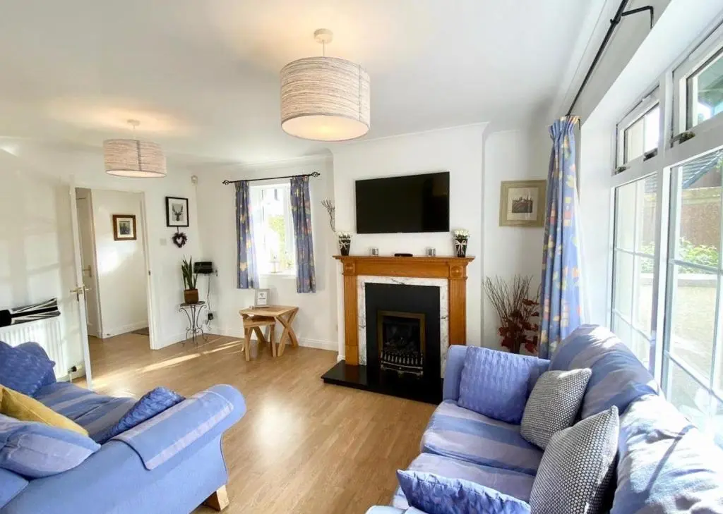 a living room with two blue couches and a fireplace at Wellingtonia Court Apartment in Inverness