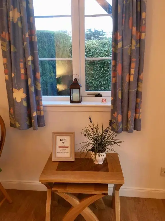 a table in front of a window with curtains at Wellingtonia Court Apartment in Inverness