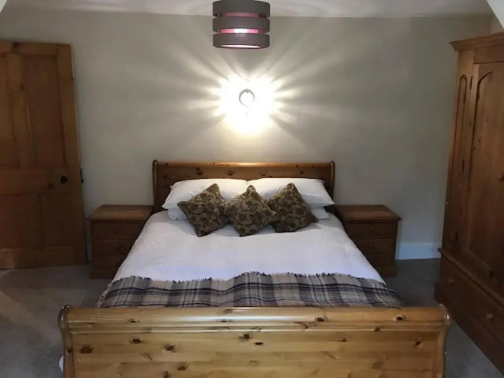 a bedroom with a wooden bed with pillows on it at Traditional Family Home in Royal Deeside in Aboyne