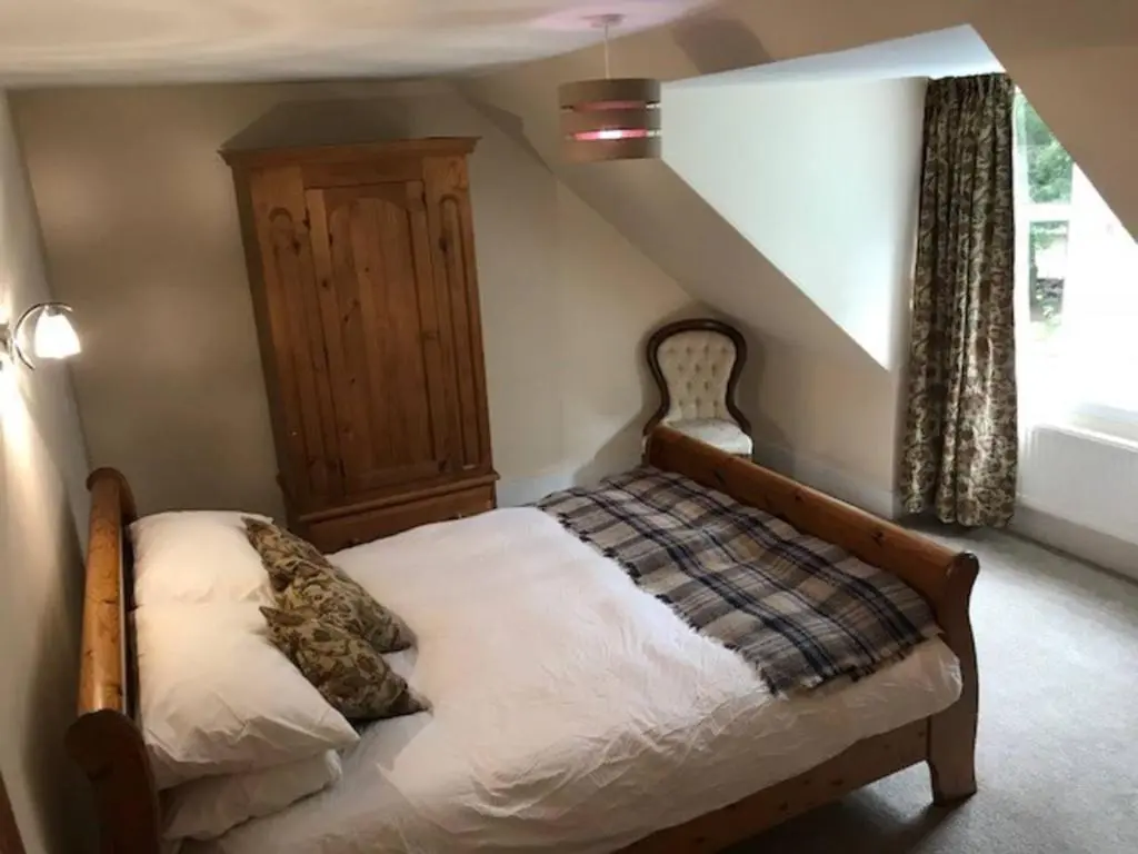 a bedroom with a bed with a wooden head board at Traditional Family Home in Royal Deeside in Aboyne