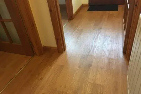 a hallway with a hard wood floor and a room with a door at Sunbury Aviemore in Aviemore