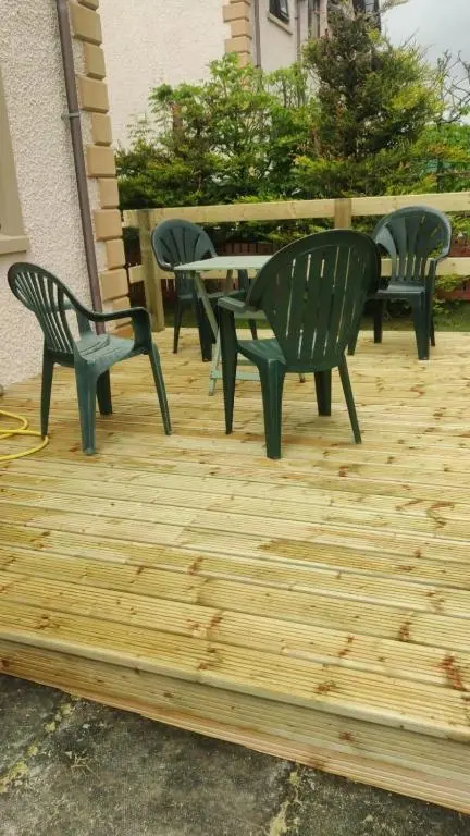 four green chairs and a table on a wooden deck at Sunbury Aviemore in Aviemore