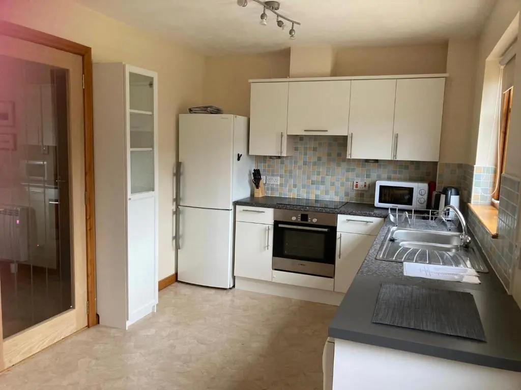 a kitchen with a white refrigerator and a sink at Sunbury Aviemore in Aviemore