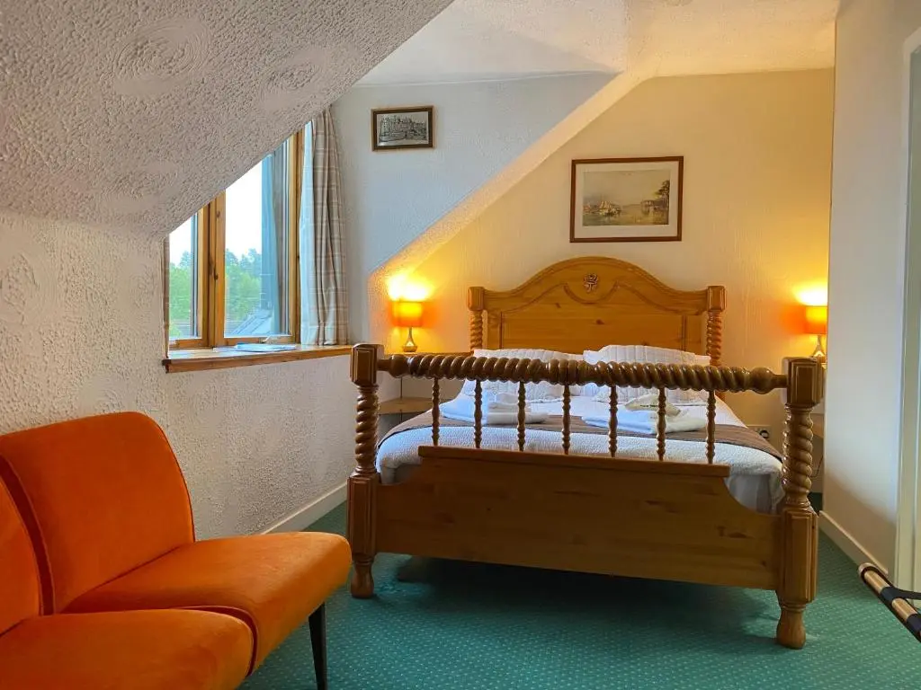 a bedroom with a wooden bed and a chair at Garden Park Guest House in Grantown on Spey