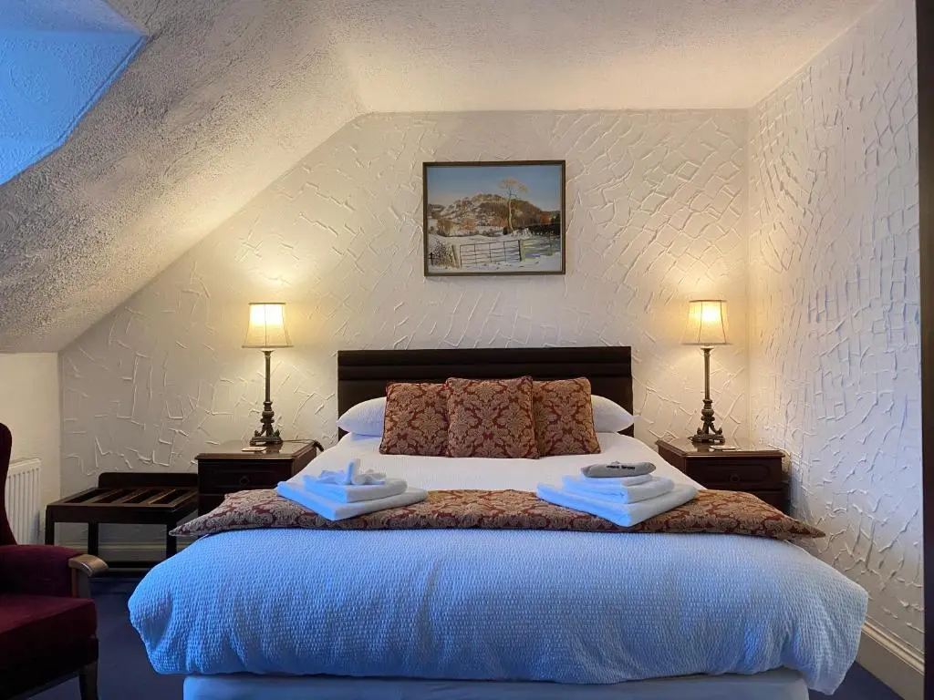 a bedroom with a large bed with two lamps at Garden Park Guest House in Grantown on Spey