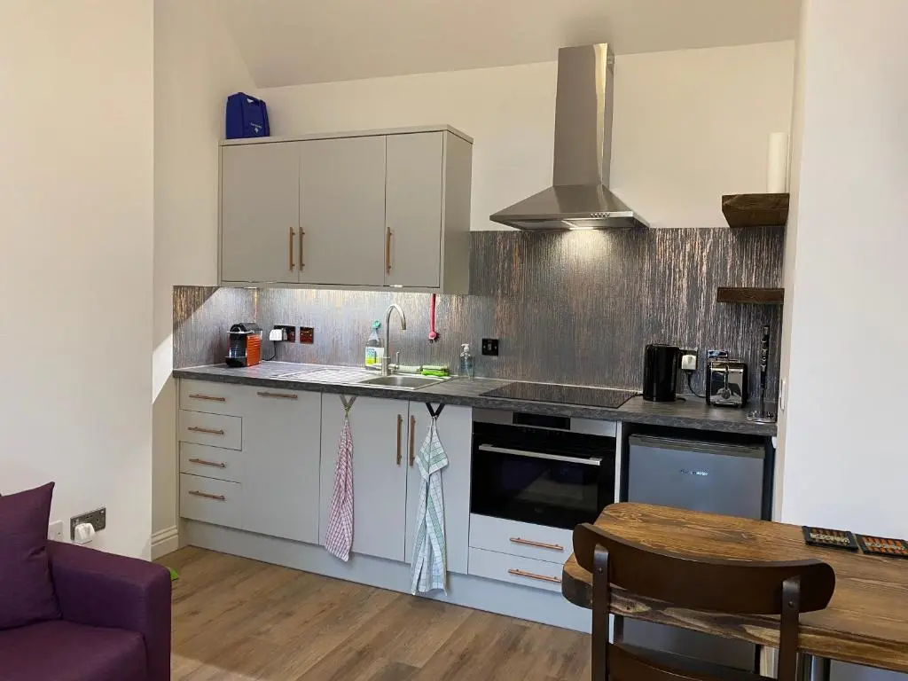 a kitchen with white cabinets and a stove top oven at Garden Park Guest House in Grantown on Spey