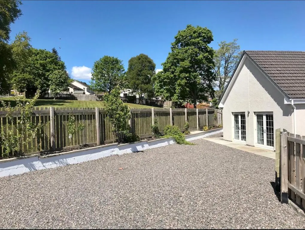 a fence in front of a house with a driveway at Lindfields in Inverness