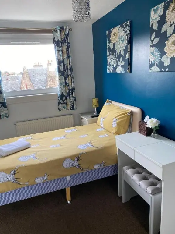 a bedroom with a bed with a yellow blanket and a window at No 29 Bed and Breakfast in Inverness