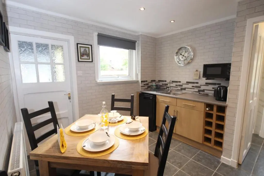 a kitchen with a wooden table with chairs and a dining room at Arrandale in Inverness