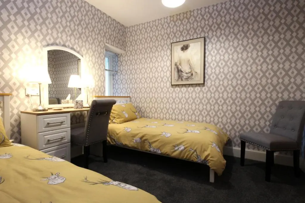 a hotel room with two beds and a desk and a bed and a mirror at Arrandale in Inverness