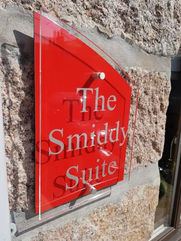 a red sign on the side of a building at The Smiddy Suite in Ellon