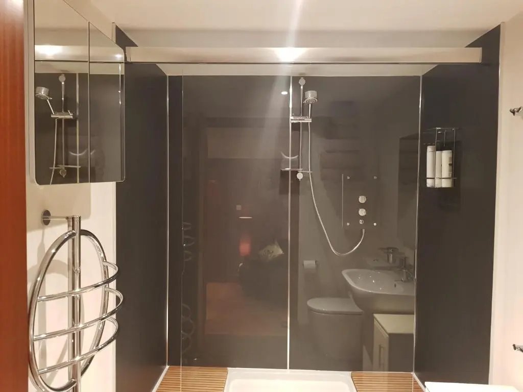 a bathroom with a glass shower with a toilet and a sink at The Smiddy Suite in Ellon