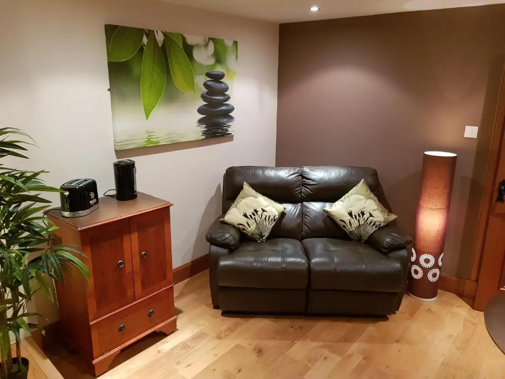 a living room with a leather couch and a table at The Smiddy Suite in Ellon