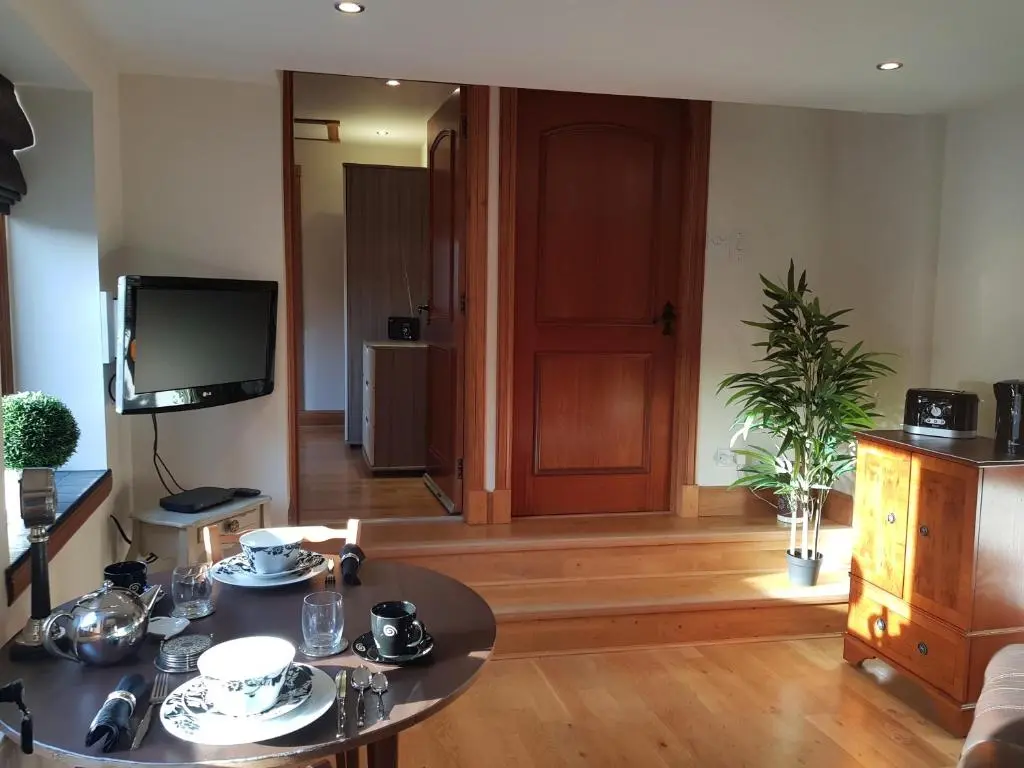 a living room with a table and a tv at The Smiddy Suite in Ellon