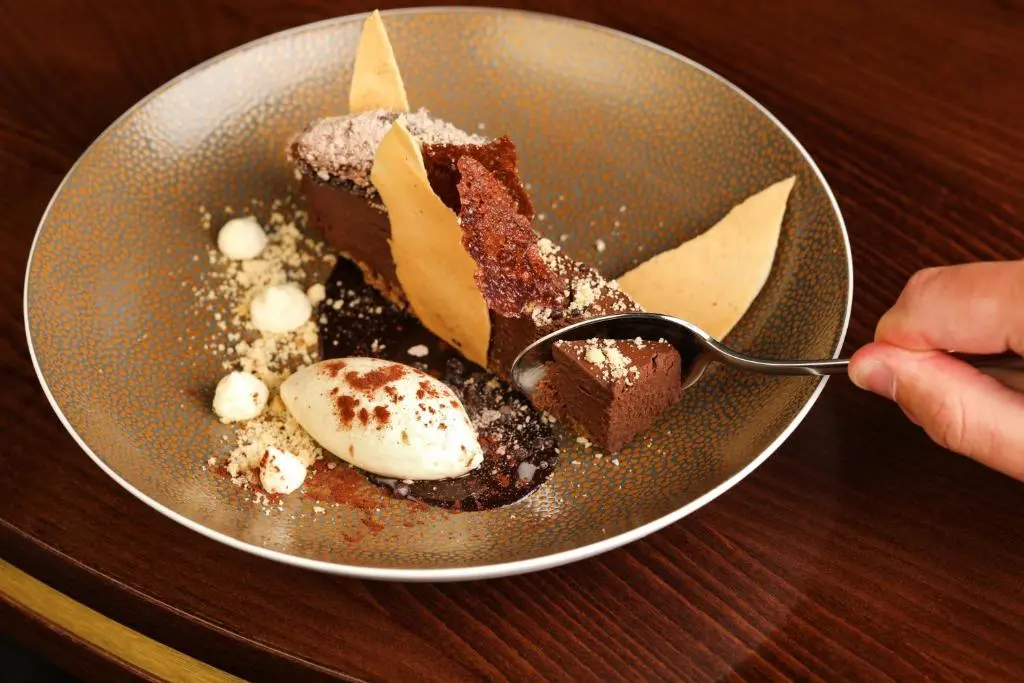 a piece of chocolate cake on a plate with a spoon at Meldrum House Hotel Golf And Country Estate in Oldmeldrum