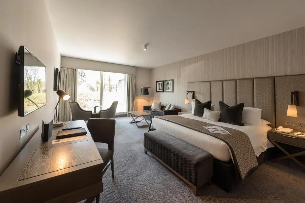 a bedroom with a large bed and a living room at Meldrum House Hotel Golf And Country Estate in Oldmeldrum