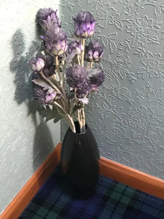 a black vase with purple flowers in it at Wimberley House in Inverness