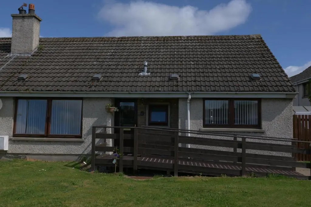 a house with a wooden fence in front of it at Kirkside Holiday Home in Alness