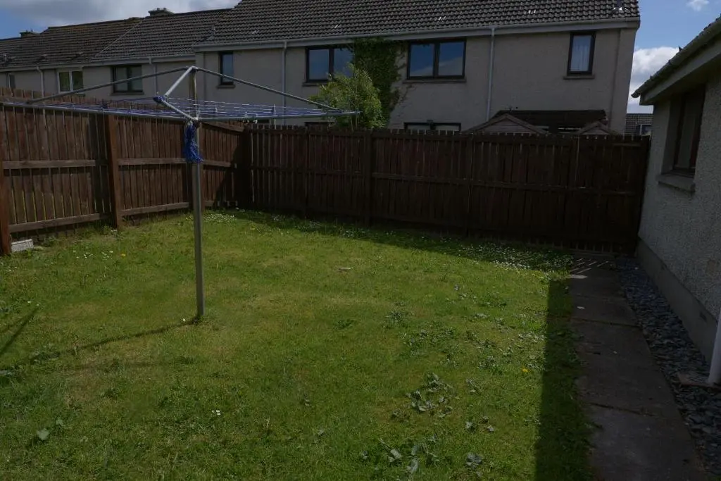 a pole in a yard in front of a fence at Kirkside Holiday Home in Alness