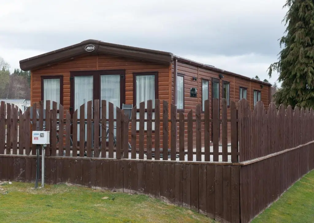 a wooden cabin behind a fence at Ruapehu Lodge in Aviemore