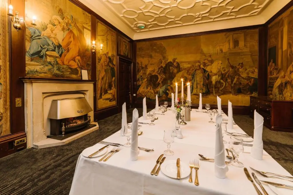 a long table in a room with a fireplace at Inverness Lochardil House, by Highland Coast Hotels in Inverness