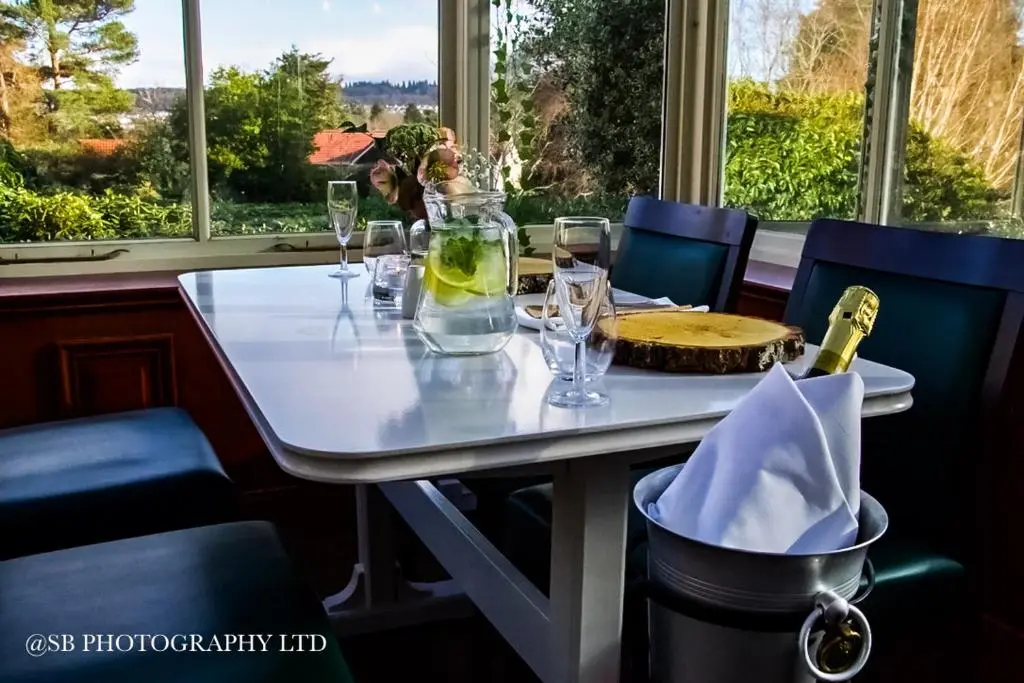 a table with glasses and a bottle of wine on it at Inverness Lochardil House, by Highland Coast Hotels in Inverness