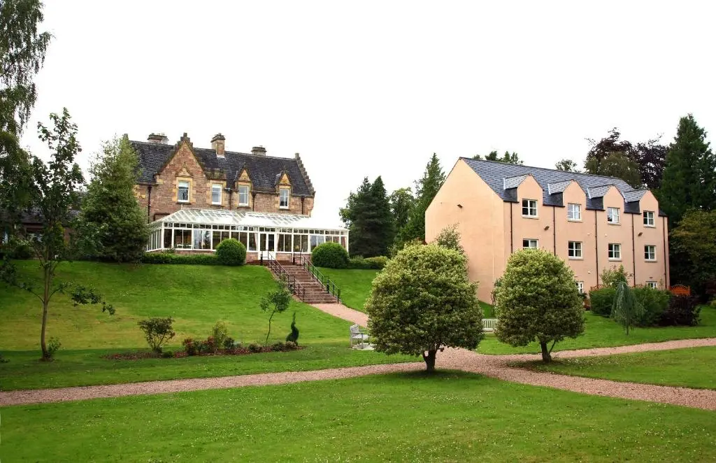 a large house on a hill with trees in front of it at Inverness Lochardil House, by Highland Coast Hotels in Inverness