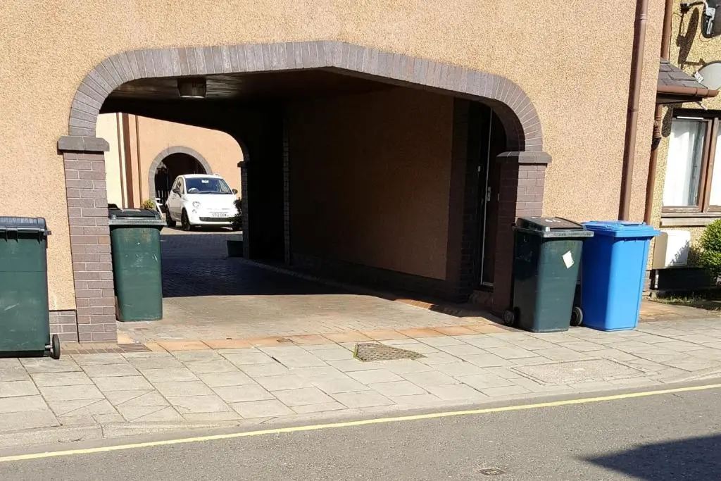 an open door to a building with two trash cans at exploreNESS Apartment in Inverness