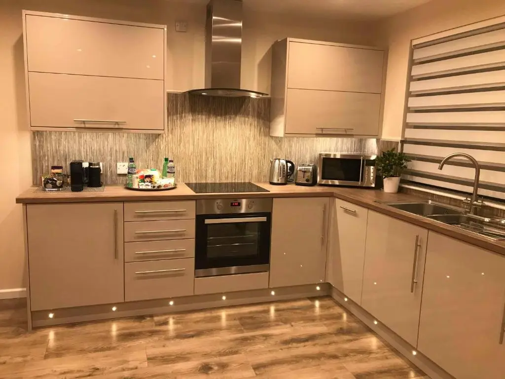 a kitchen with stainless steel appliances and wooden floors at exploreNESS Apartment in Inverness