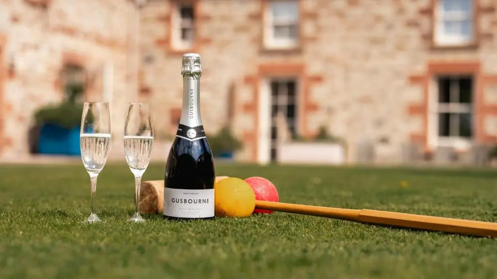a bottle of wine and two champagne glasses on the grass at Newhall Mains in Resolis