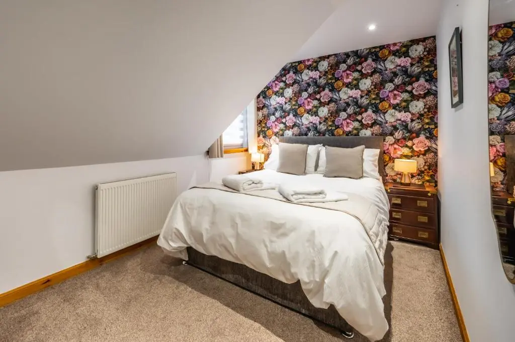 a bedroom with a large bed with a floral wall at Aldo's Place in Dingwall