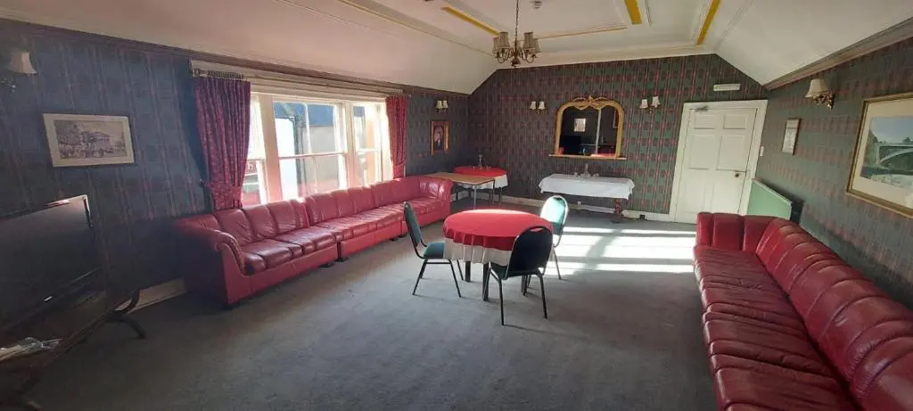 a living room with red couches and a table and chairs at Gordon Arms Hotel in Fochabers