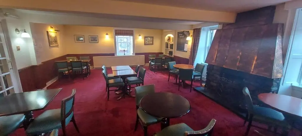 a restaurant with tables and chairs and a fireplace at Gordon Arms Hotel in Fochabers