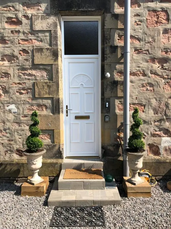 a white door on a stone building with two plants at Period House / Entire Upstairs Flat in Inverness