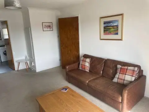 a living room with a brown couch and a coffee table at Number 5, Muirfield Court in Inverness
