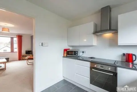 a kitchen with white cabinets and a stove top oven at Number 5, Muirfield Court in Inverness