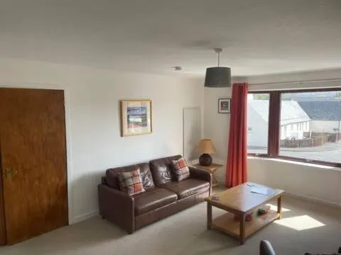 a living room with a brown couch and a table at Number 5, Muirfield Court in Inverness
