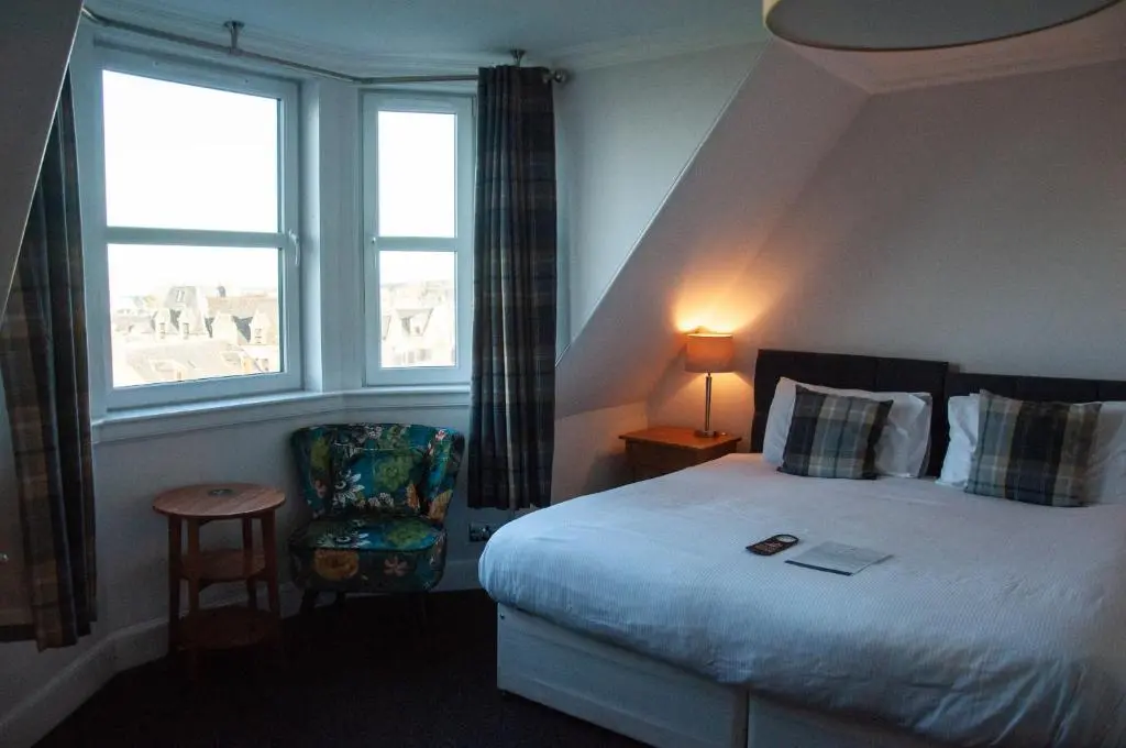 a bedroom with a bed and a window and a chair at The Bandstand in Nairn